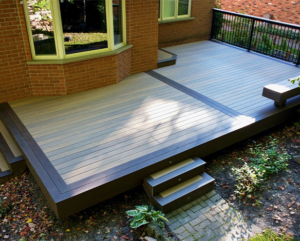 Custom composite decking with aluminum deck railing and 2 sets of steps leading towards garden in backyard.